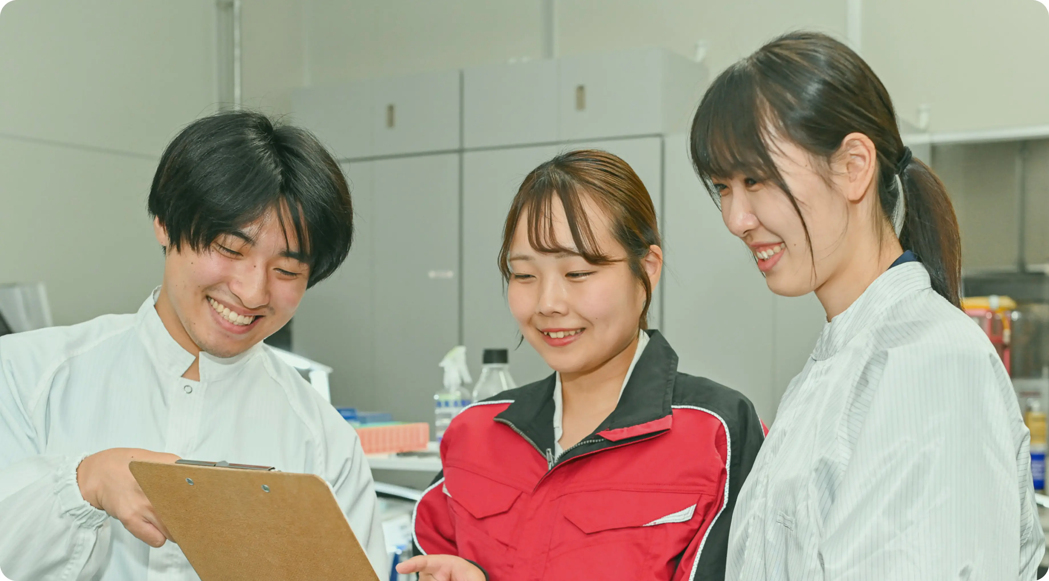 研究者3名が実験室で笑顔で話し合っている様子